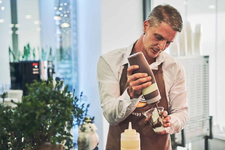 JP Gastro Mitarbeiter bereitet ein Eis mit Schokosauce zu