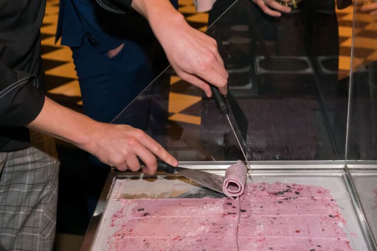 Ein Mitarbeiter schneidet gerade Eis zurecht und rollt es auf