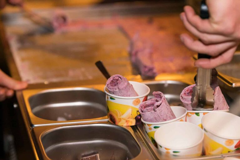 Frisch zubereitete Ice Cream Rollen, die in kleinen Bechern angerichtet werden