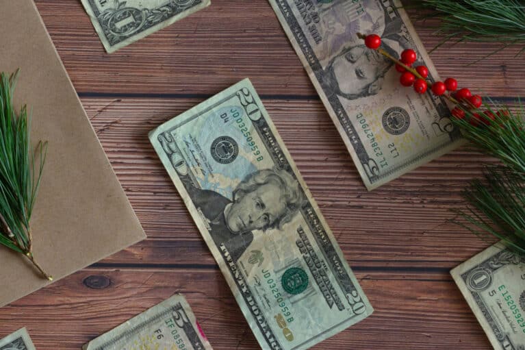 Ein Holztisch auf dem weihnachtliche Dekoration und Dollarscheine liegen