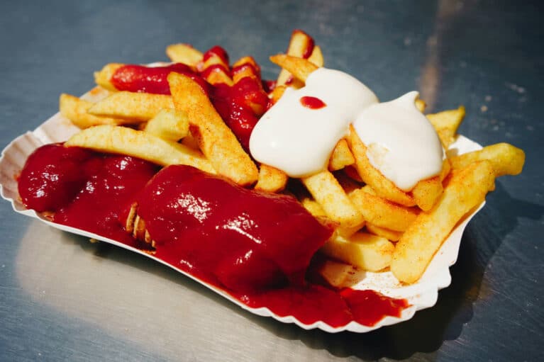 Eine Portion Currywurst mit Pommes in einem Schälchen