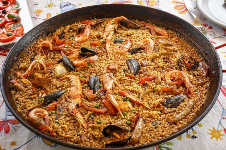 Eine große Paella-Pfanne mit Reis, Garnelen und Muscheln.